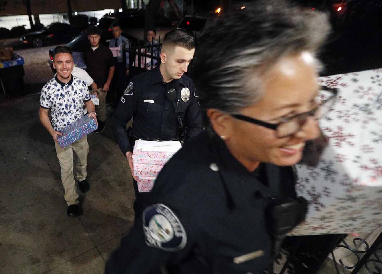 Glendale police officer Michelle Gonzalez leads her group of several volunteers into the apartment of the Zarate family, the first stop for the annual Glendale Police Officerâ€™s Associationâ€™s Cops for Kids program at the Glendale Police Department on Tuesday, December 18, 2018. The program has reduced in size, delivering to fourteen families, while last year there where thirty.