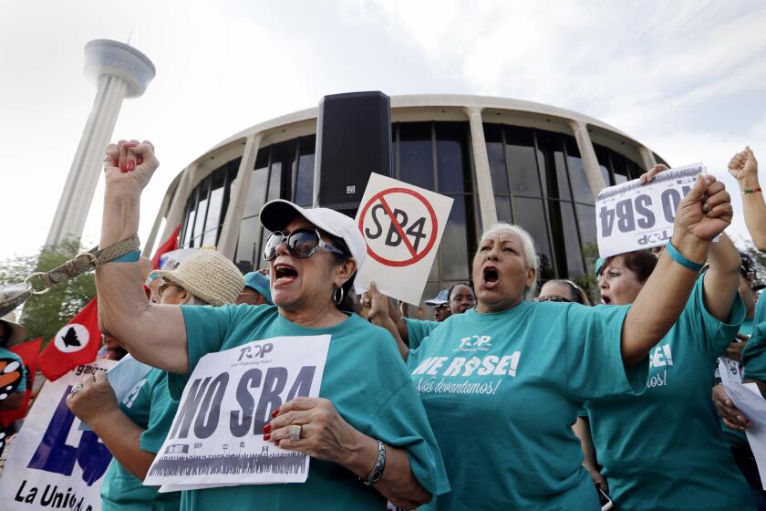 FILE - In this June 26, 2017, file photo, Lydia Balderas, left, and Merced Leyua, right, join others as they protest against a new sanctuary cities bill outside the federal courthouse in San Antonio. Even as a new Texas law targeting so-called sanctuary cities remains in legal limbo, police chiefs and sheriffs are making changes to comply, rewriting training manuals and withdrawing policies that prevented officers from asking people whether they're in the United States illegally. The law, known as Senate Bill 4, goes into effect Sept. 1 unless a federal judge in San Antonio blocks it. (AP Photo/Eric Gay, File)