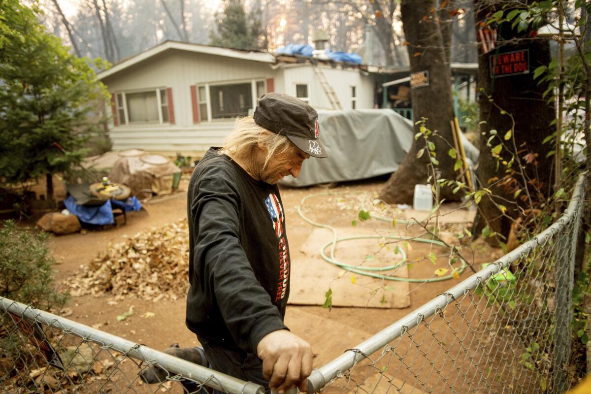 Jimmy Clements, who stayed at his home as the Camp fire raged through Paradise, Calif., leans against his fence.