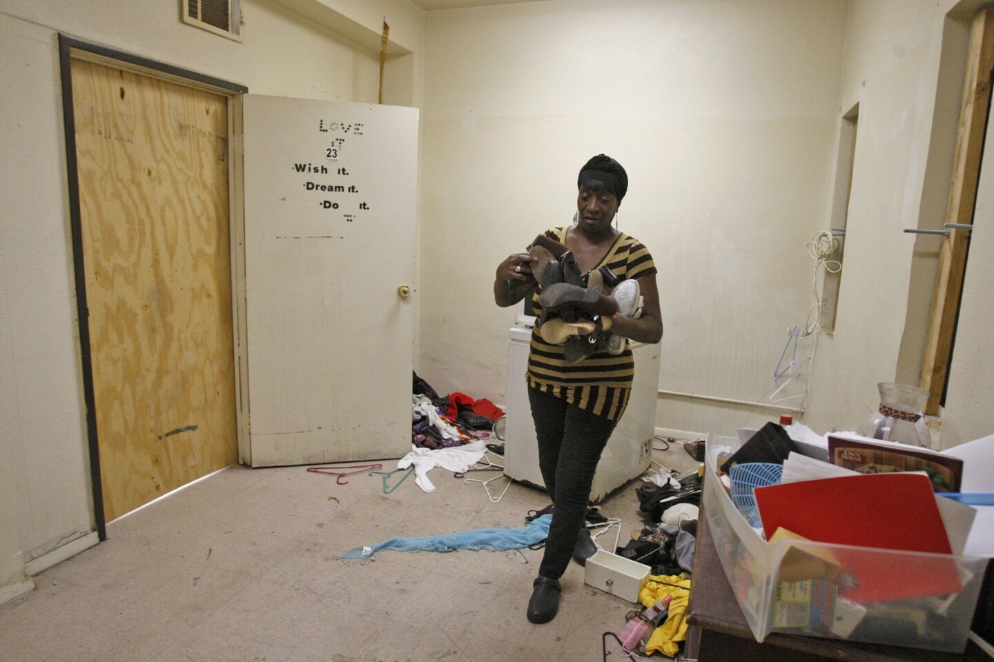 Patricia McDowell, 57, cleans up a storage area connected to her apartment in what was once office space that was converted into apartments at 5700 S. Hoover St. in Los Angeles. McDowell and her neighbors were told on short notice that they must vacate the building because of safety hazards.