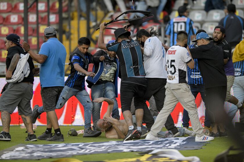 Fans clash during a Mexican soccer league match between the host Queretaro and Atlas from Guadalajara, at the Corregidora stadium, in Queretaro, Mexico, Saturday, March 5, 2022. Multiple people were injured during the brawl, including two critically. (AP Photo/Sergio Gonzalez)