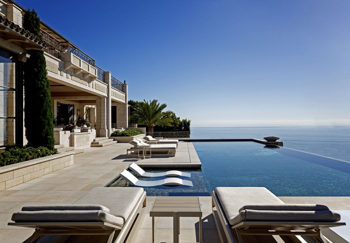 Exterior of mansion with deck, pool and view of the ocean.