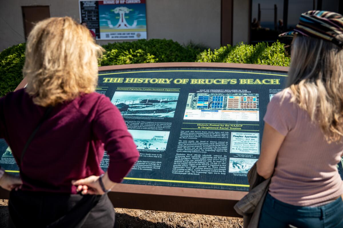 People read about the history of Bruce's Beach on an informational display in Manhattan Beach.