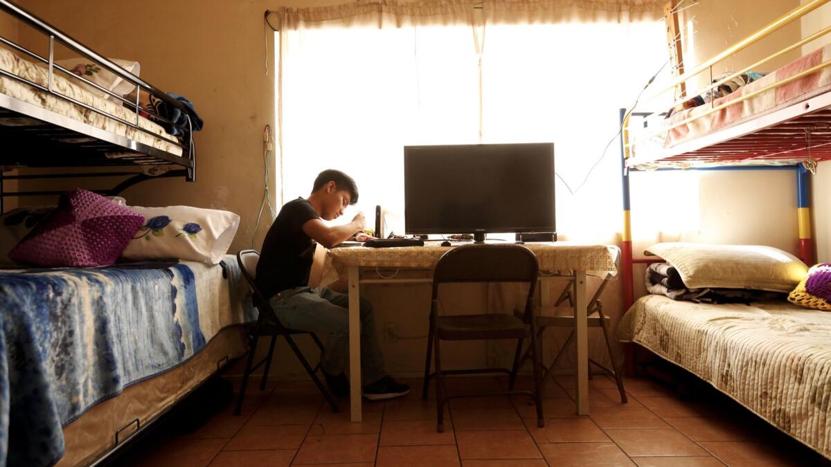 Noe Martinon, 18, does his homework between two sets of bunk beds in a space that is both bedroom and living room for him and his family.
