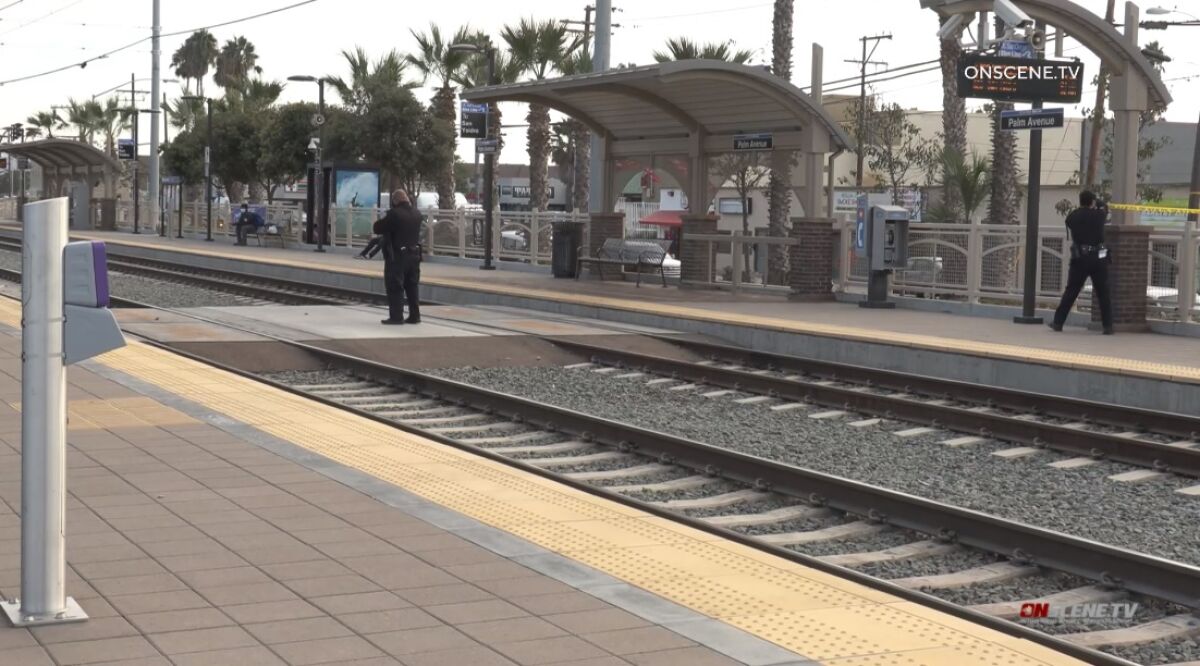 SDPD officers string up crime scene tape Saturday at the Palm Avenue trolley station after a man was stabbed at the site.
