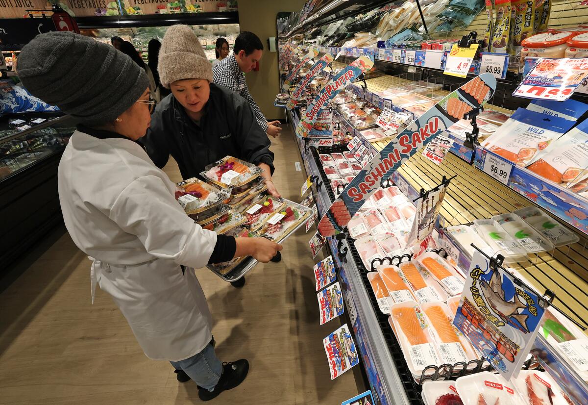 Workers stock shelves of various fresh sushi during grand opening of the Tokyo Central supermarket in Irvine July 26.