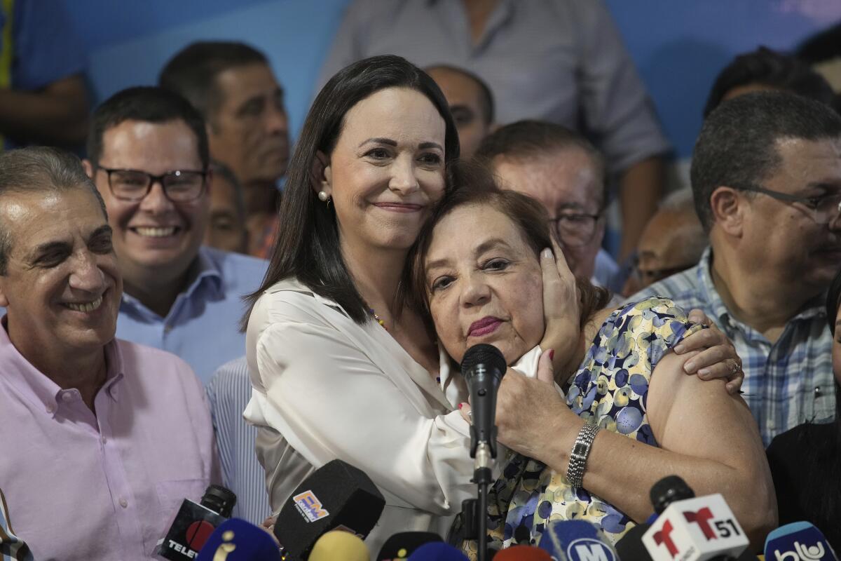 Two women embrace at a news conference.