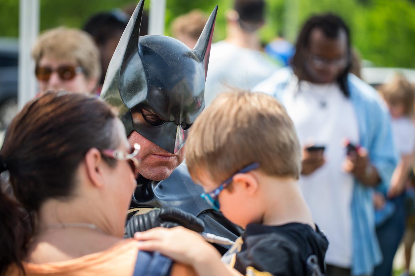 Leonard Robinson, as Batman, greets crowds of people after arriving at the Miller Branch Library in his Batmobile to kick off the Howard County Library System's summer reading program.