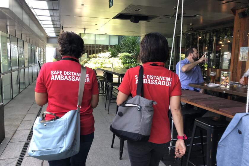 Safe distancing ambassadors Rugayah Noordin and Fiona Tay walk past a bar in Singapore.