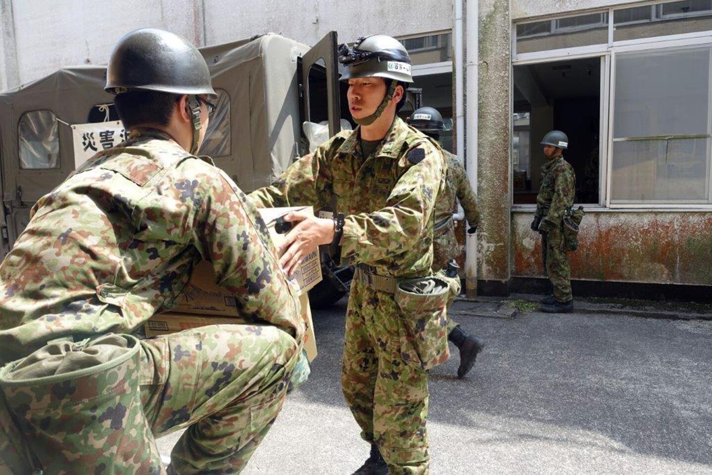 Troops bring in supplies to set up a new shelter in Minamiaso, Kumamoto prefecture, Japan Tuesday, April 19, 2016. Evacuees at a gymnasium were moving to another shelter Tuesday, a nearby former elementary school, because some expressed fears after the strong aftershock, because the gym stands on the hill.