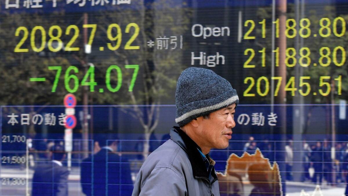 A pedestrian passes a stock market board in Tokyo after stocks plunged.
