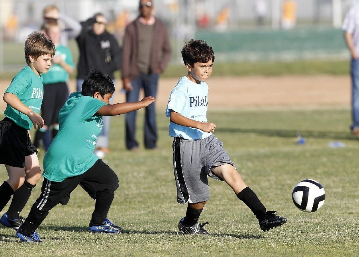 Newport Heights' William Haide, right, kicks the ball during a Daily Pilot Cup boys' third- and fourth-grade silver division game against Lincoln on Tuesday.
