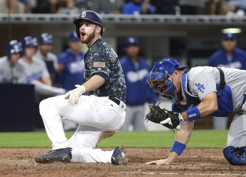The Padres' Cory Spangenberg looks up for the call after trying to score at home plate while Dodgers' catcher A.J. Ellis gets up in the sixth inning. Spangenberg was ruled out. The call would be upheld after an official review.