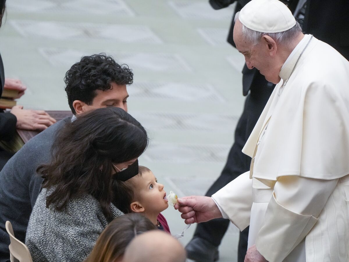 Pope Francis takes the pacifier of a baby during his weekly general audience in the Paul VI Hall at the Vatican, Wednesday, Feb. 23, 2022. (AP Photo/Gregorio Borgia)
