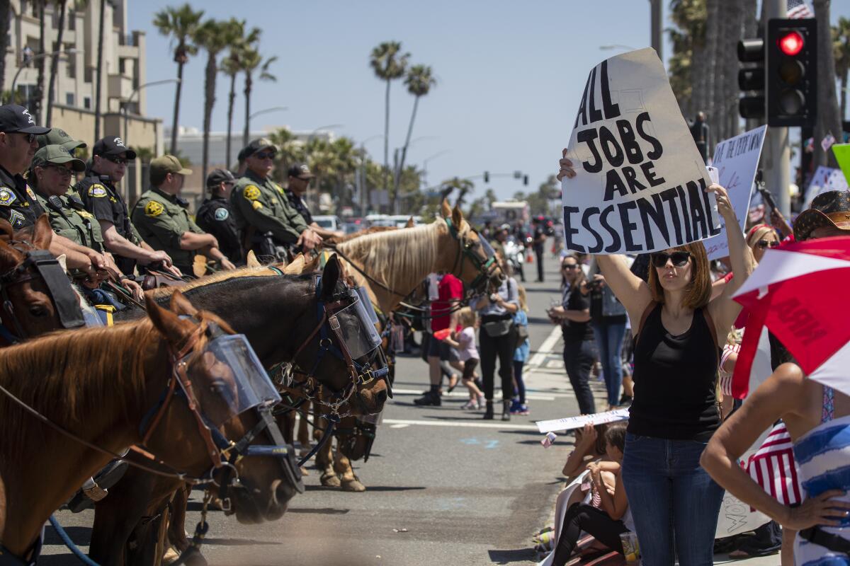 Mounted police line up to keep protesters on the sidewalk as thousands of people ters rally at the intersection of Main Street and Pacific Coast Highway Huntington Beach.