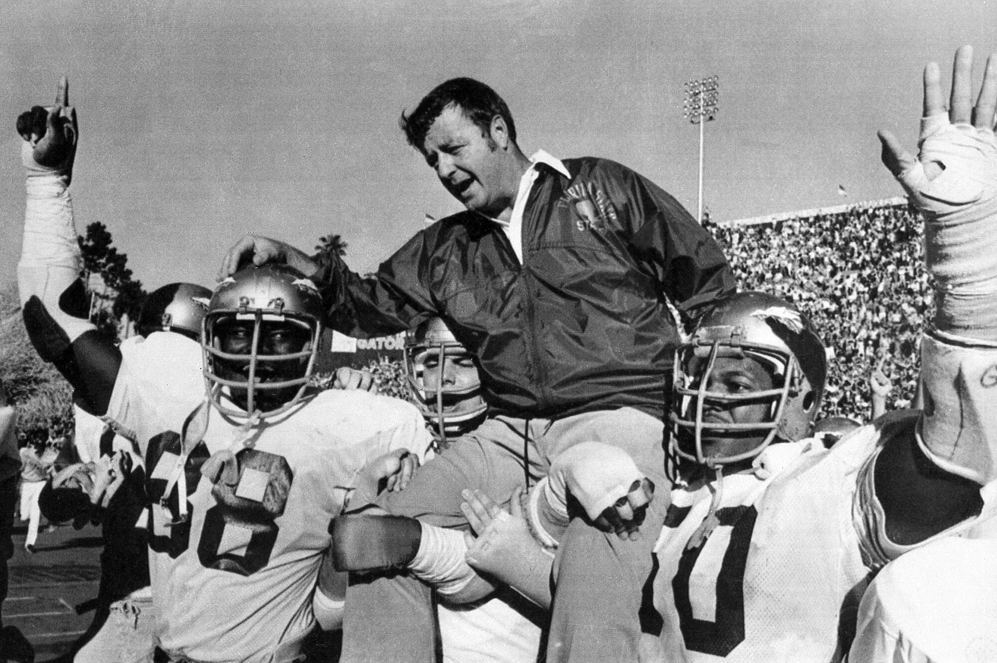 In a black-and-white photo, Bobby Bowden is carried on the shoulders of football players.