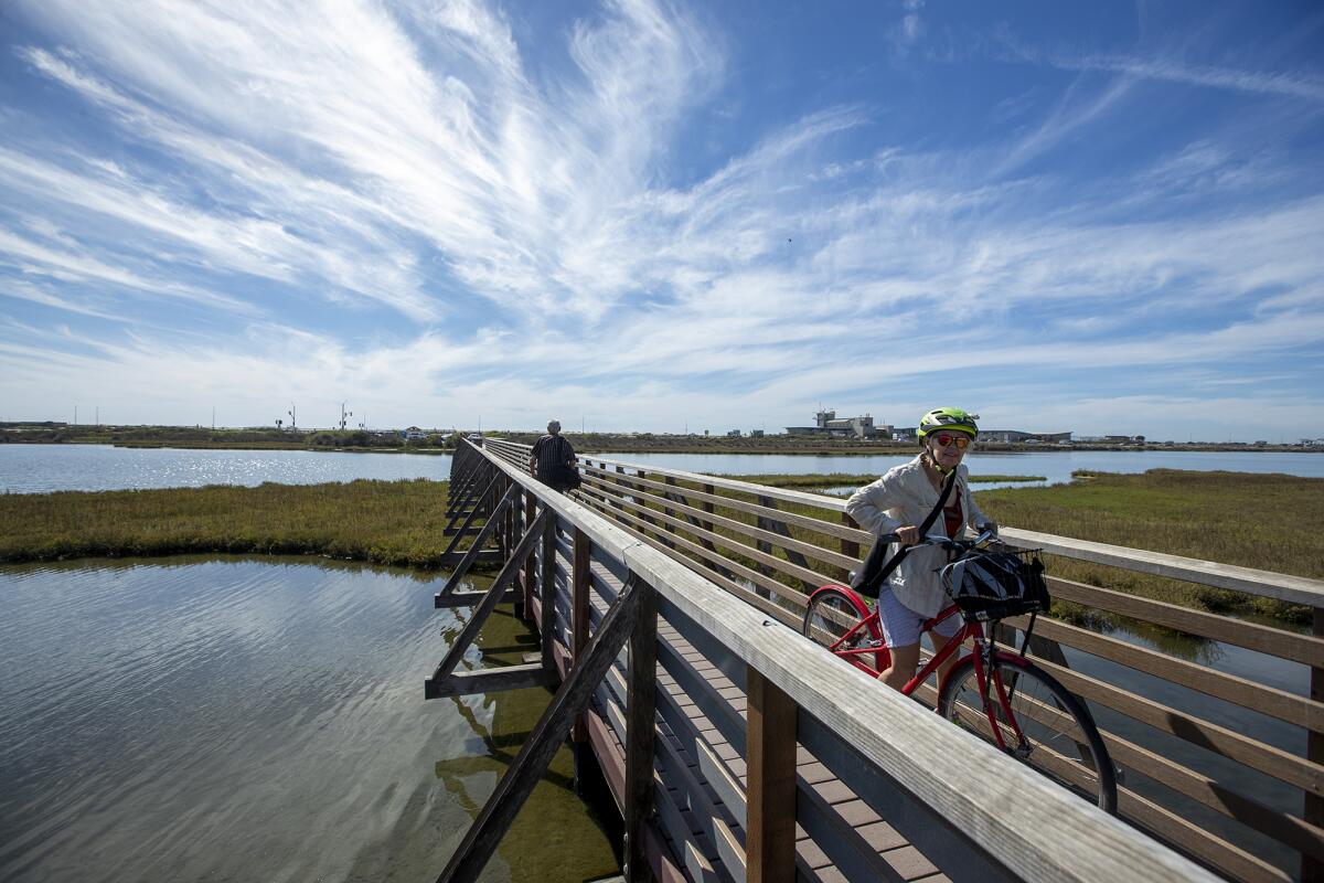 Annette Mangaard, from Toronto, Canada rides her bike across a bridge at the Bolsa Chica Ecological Reserve in March 2022.