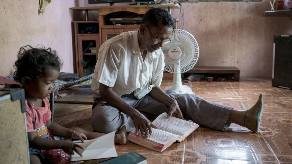 Sok Sem, 58, reads the Bible with his daughter Sok Sreypao, age 4. Sok was a commander of a special military unit of the Khmer Rouge. He committed to Christianity in 2001.