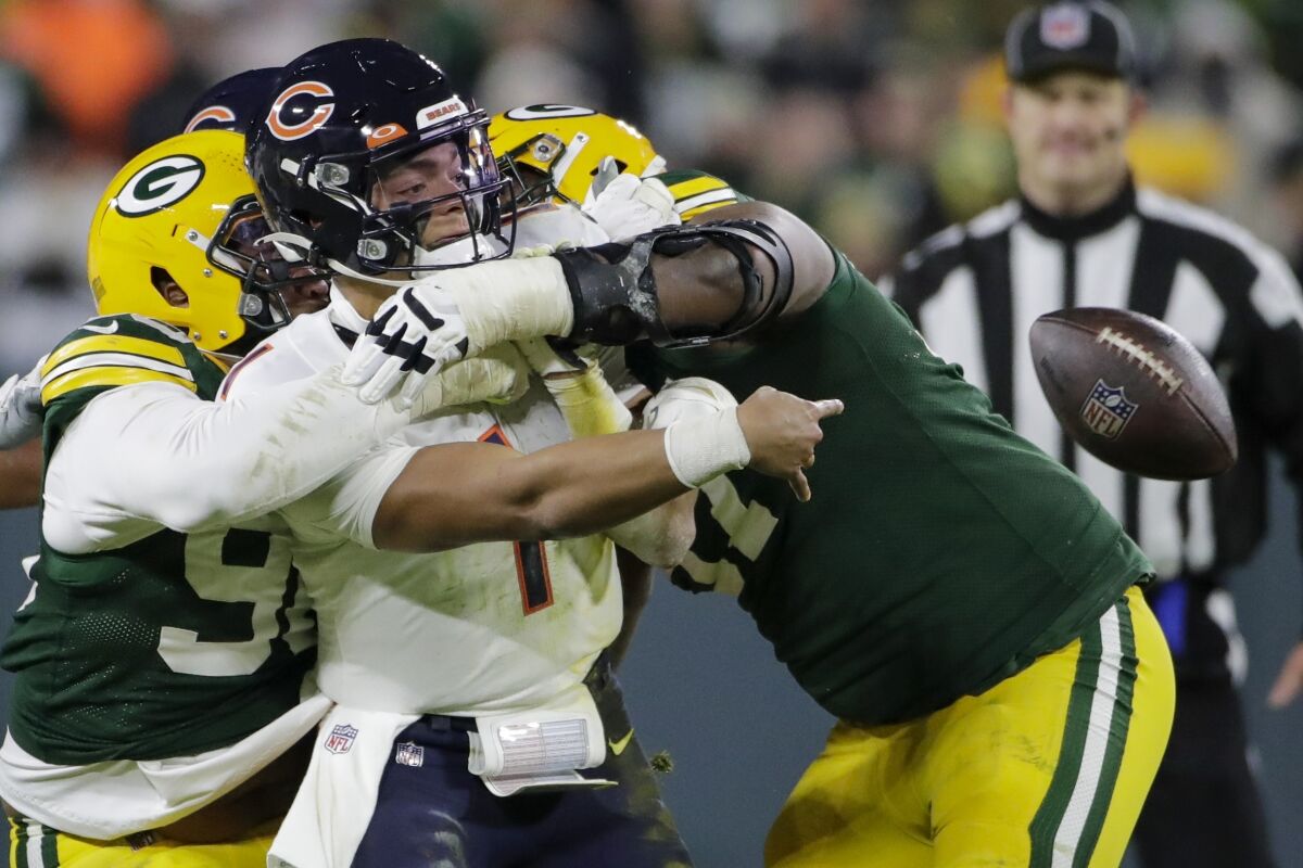 Chicago Bears' Justin Fields flips the ball as he is hit by Green Bay Packers' Kingsley Keke and Kenny Clark during the second half of an NFL football game Sunday, Dec. 12, 2021, in Green Bay, Wis. (AP Photo/Aaron Gash)
