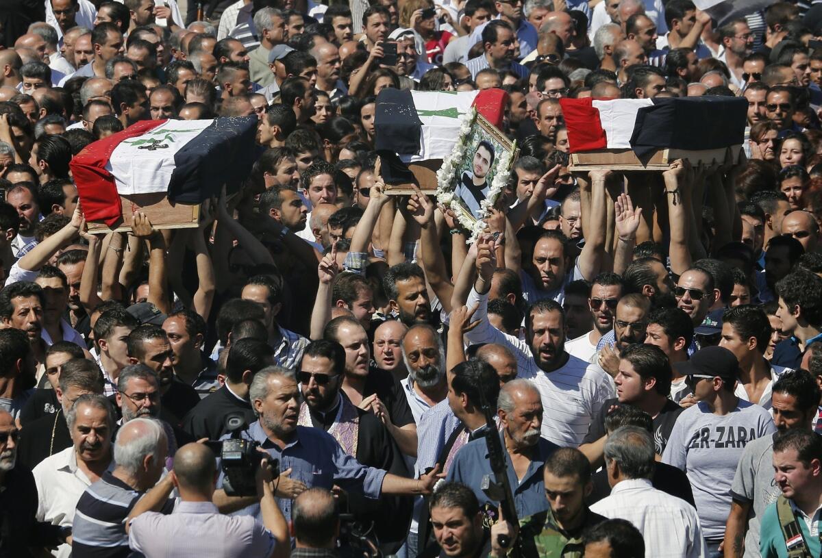 The coffins of three Syrian Christians killed last weekend in sectarian fighting in the ancient town of Maaloula are carried during a funeral march in Damascus on Tuesday. A UN Human Rights Council panel reported Wednesday that war crimes are on the rise among both Syrian government and rebel forces.