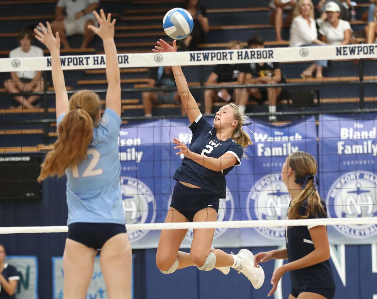 Newport Harbor's Ella Olson (2) taps a ball over the net past Matisse Robertson.