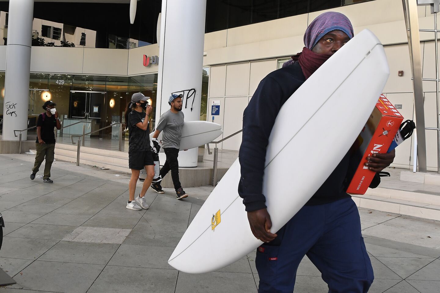 People walk away with surfboards in Santa Monica on Sunday.