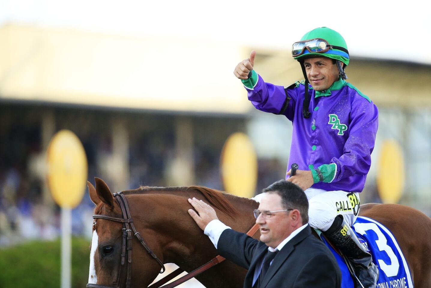 Jockey Victor Espinoza gives the thumbs-up sign as assistant trainer Alan Sherman greets California Chrome after his victory in the Preakness Stakes on Saturday at Pimlico Race Course in Baltimore.