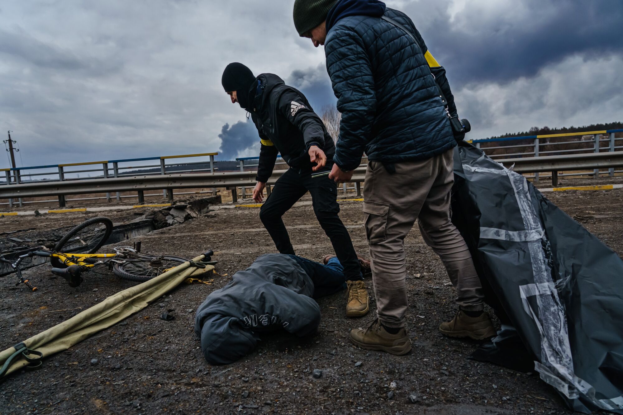 Two men prepare to move a body on the ground