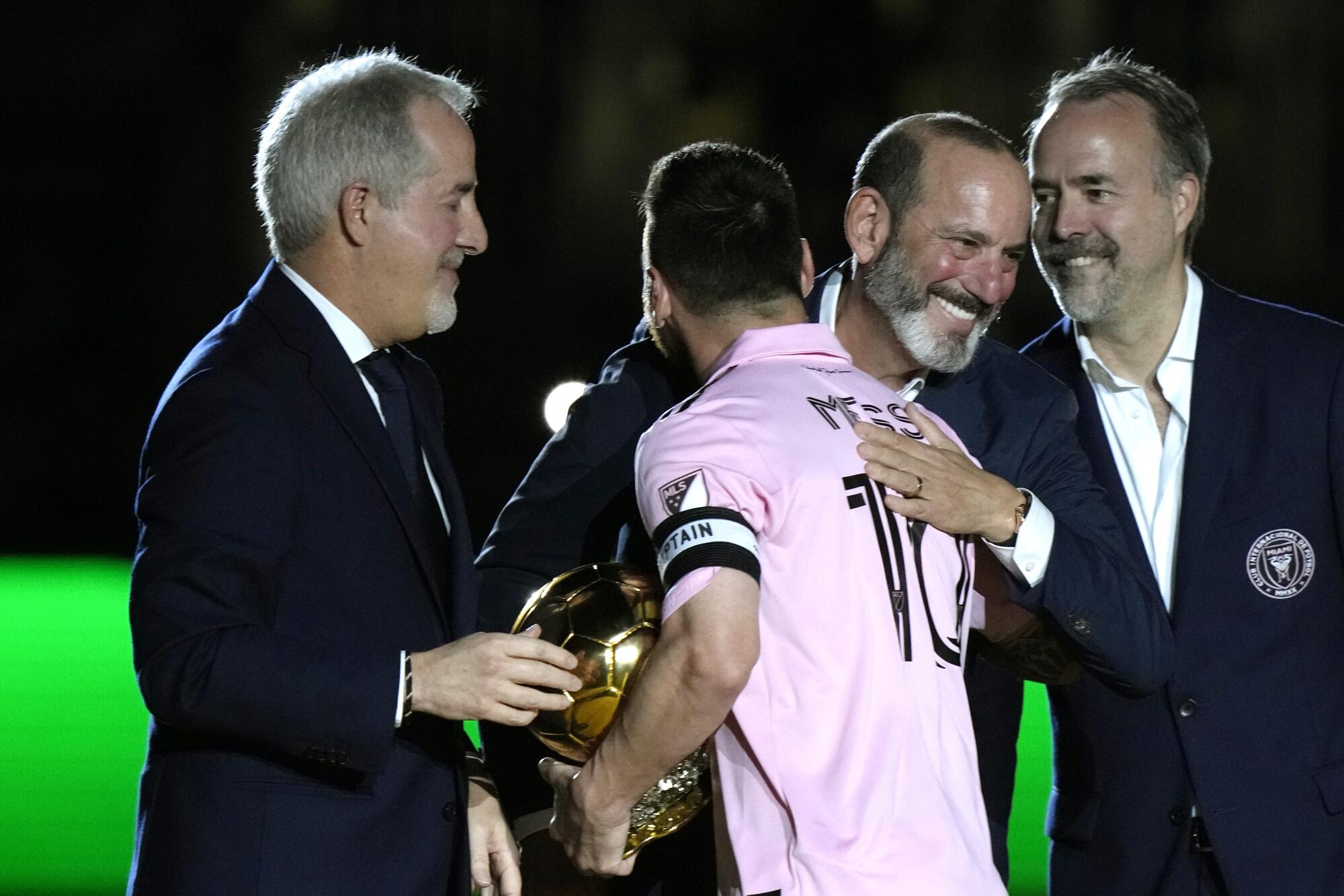 国际迈阿密前锋莱昂内尔·梅西被美国职业足球大联盟主席唐·加伯（中右）拥抱。