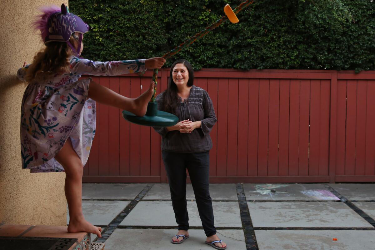 Cindy Carcamo watches on as her 5-year-old daughter plays on a swing at home in Santa Ana