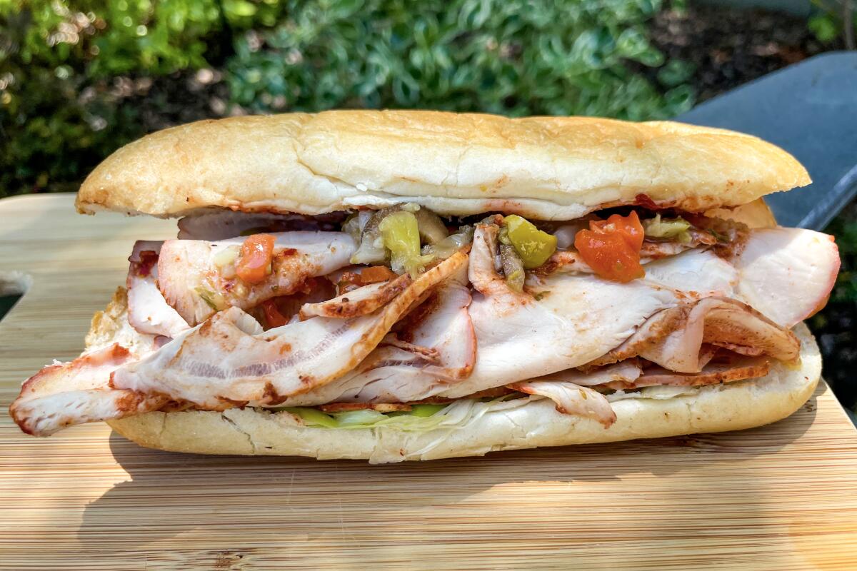 A roast pork sandwich rests on a cutting board