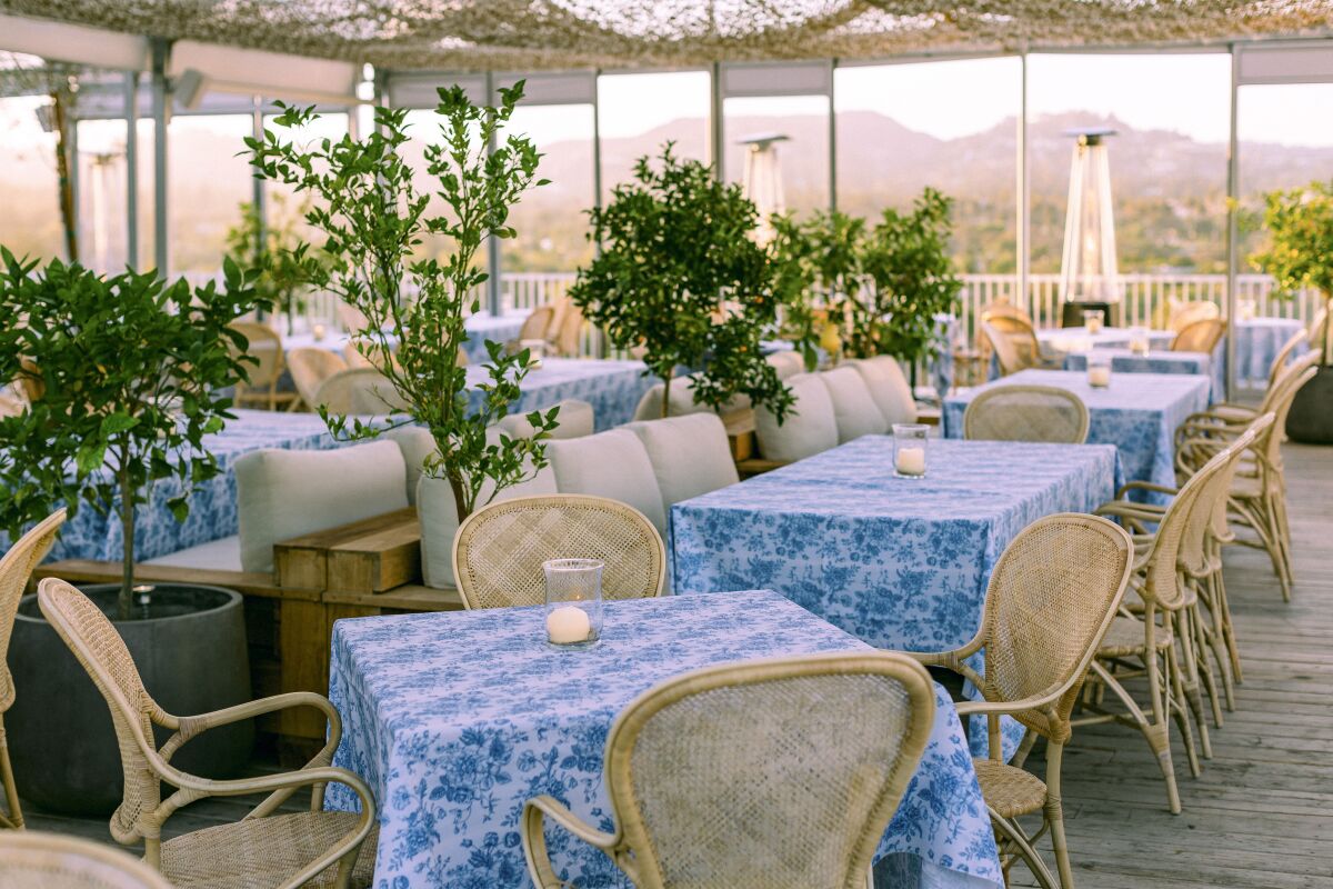 tables with blue tablecloths and wicker chairs on a rooftop 