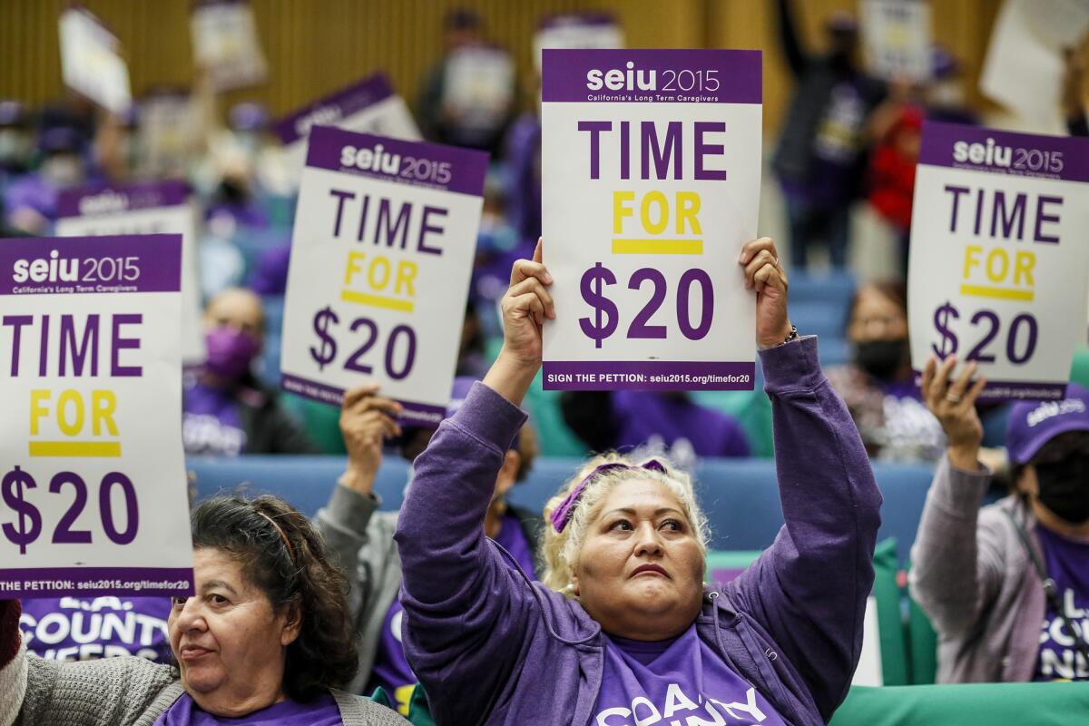Blanca Alvarez and other protesters wearing purple hold signs reading "Time For $20"