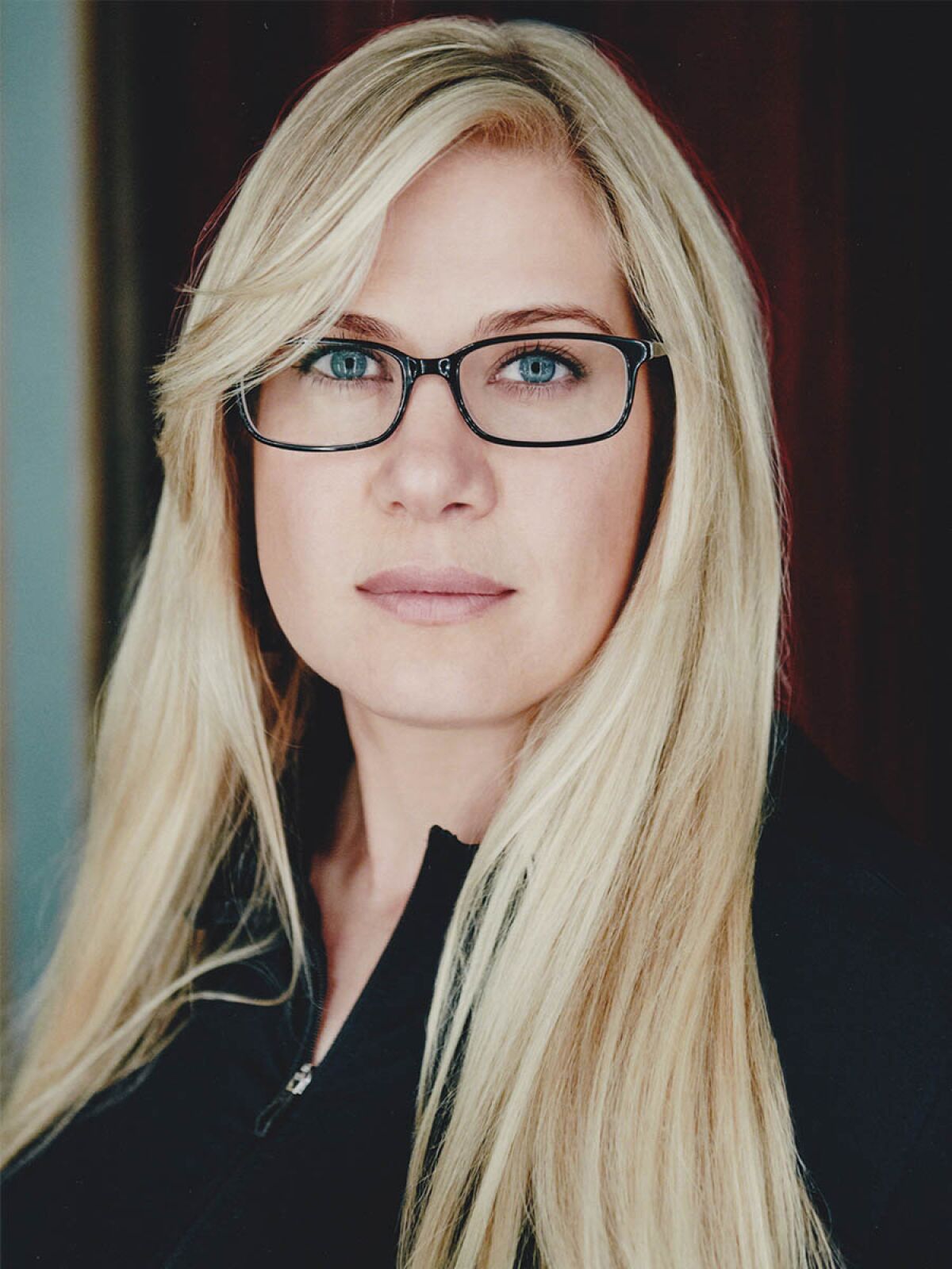 A portrait of a blond woman with glasses.