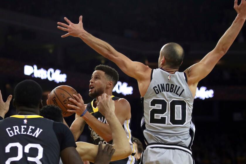 Golden State Warriors' Stephen Curry, center, looks to shoot past San Antonio Spurs' Manu Ginobili (20) during the first half of an NBA basketball game Saturday, Feb. 10, 2018, in Oakland, Calif. (AP Photo/Ben Margot)