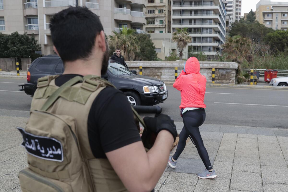 A Lebanese intelligence officer asks a jogger to clear the street in Beirut after authorities ordered shops to close for two weeks to fight the coronavirus.