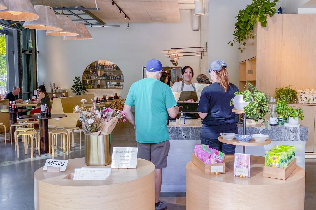 The inside of an airy restaurant with concrete floor and light colored wood.