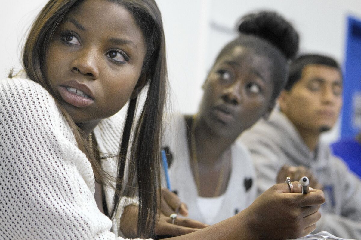 Renee Johnson, 20, from left, Robin Hall, 18, and Arnold Lopez, 18, take notes during a College Bridge class at the Brotherhood Crusade in Los Angeles.