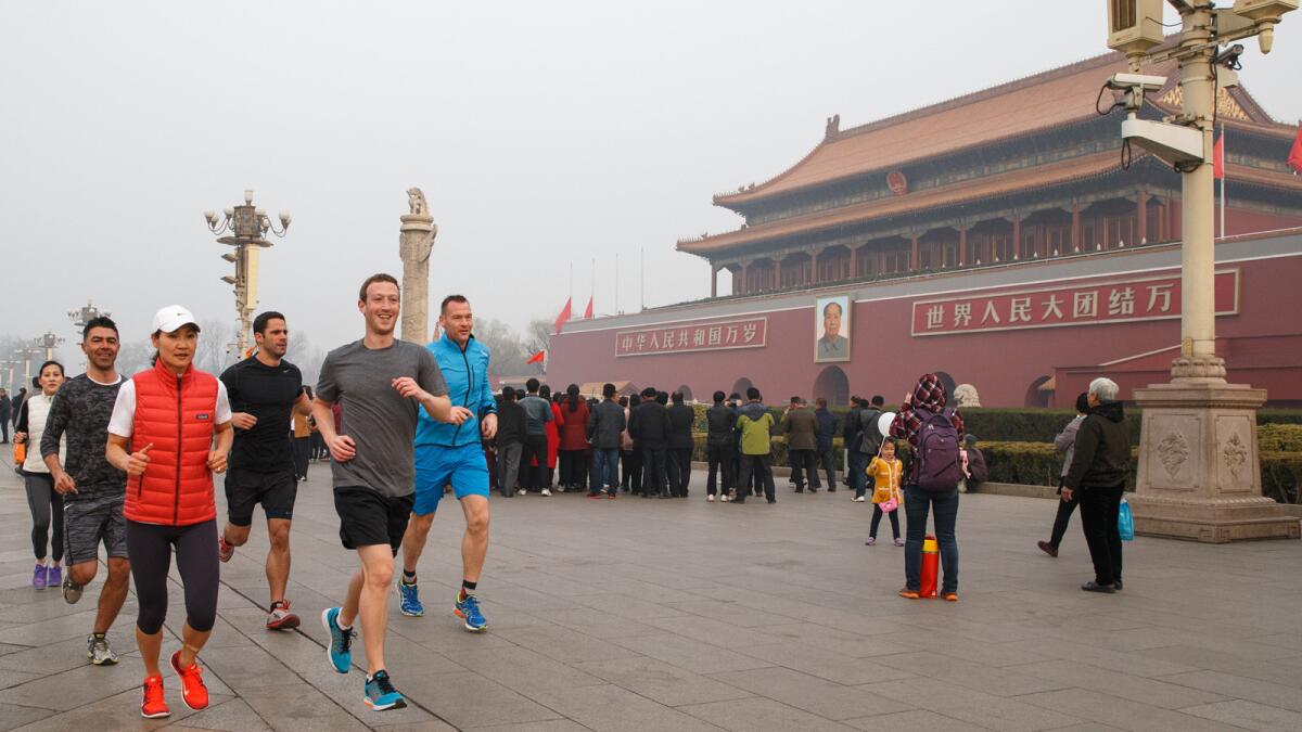 Facebook Chief Executive Mark Zuckerberg (gray shirt) runs past Tiananmen Gate in Beijing in 2016. His visit was part of an effort to court the Chinese government.