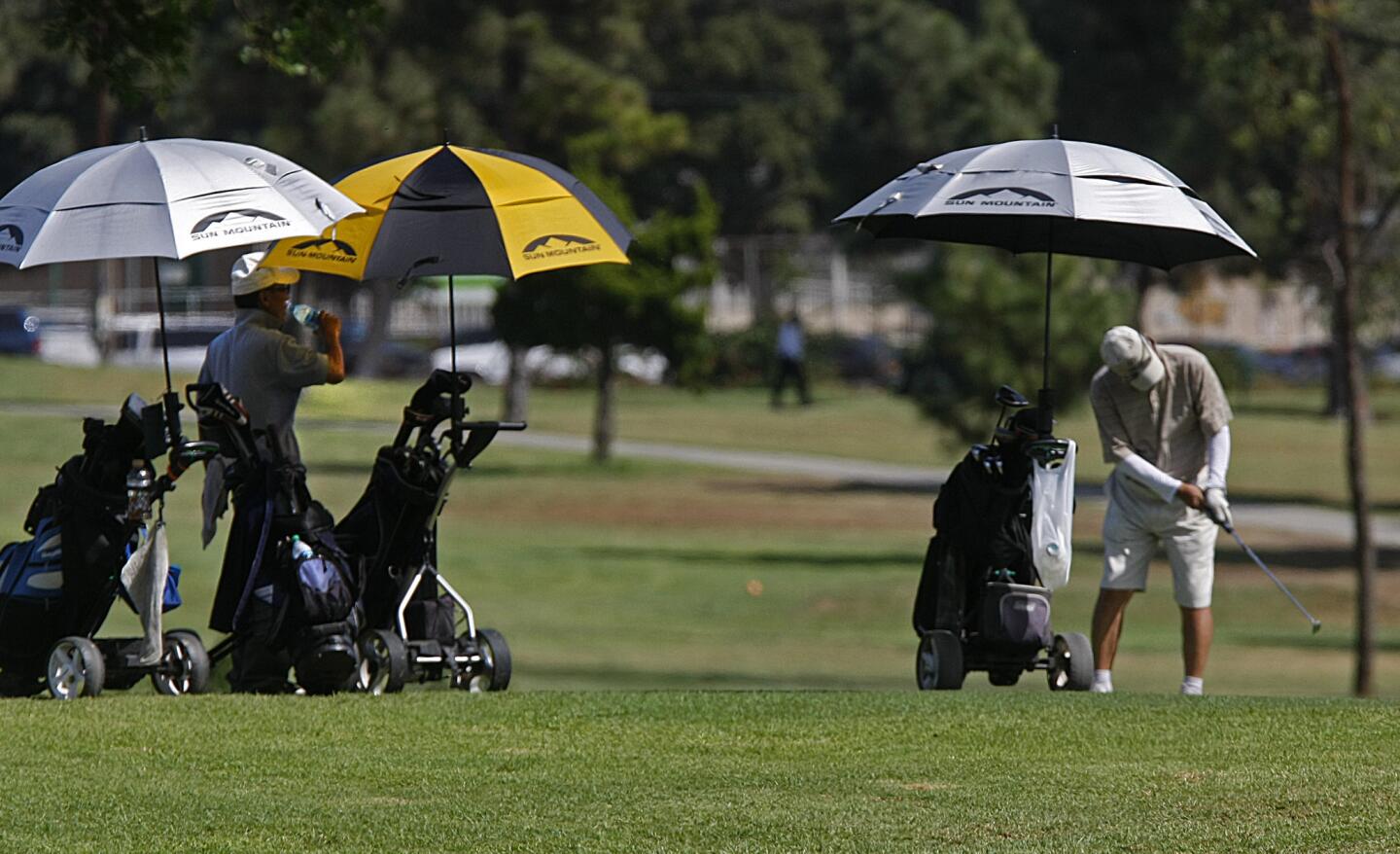 With early afternoon temperature in the mid-90s, golfers at Chester Washington Golf Course in Hawthorne carry umbrellas and ice water to beat the heat.