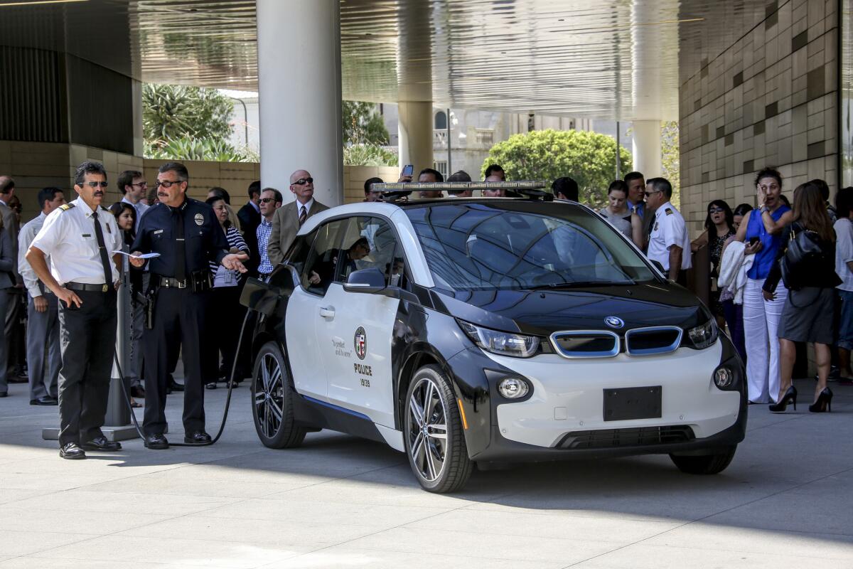 L.A. Fire Chief Ralph Terrazas, left, and LAPD Chief Charlie Beck on Friday check out a BMW electric vehicle at LAPD headquarters before a news conference at which the mayor offered up details about the city's plan to bolster the use of electric vehicles.