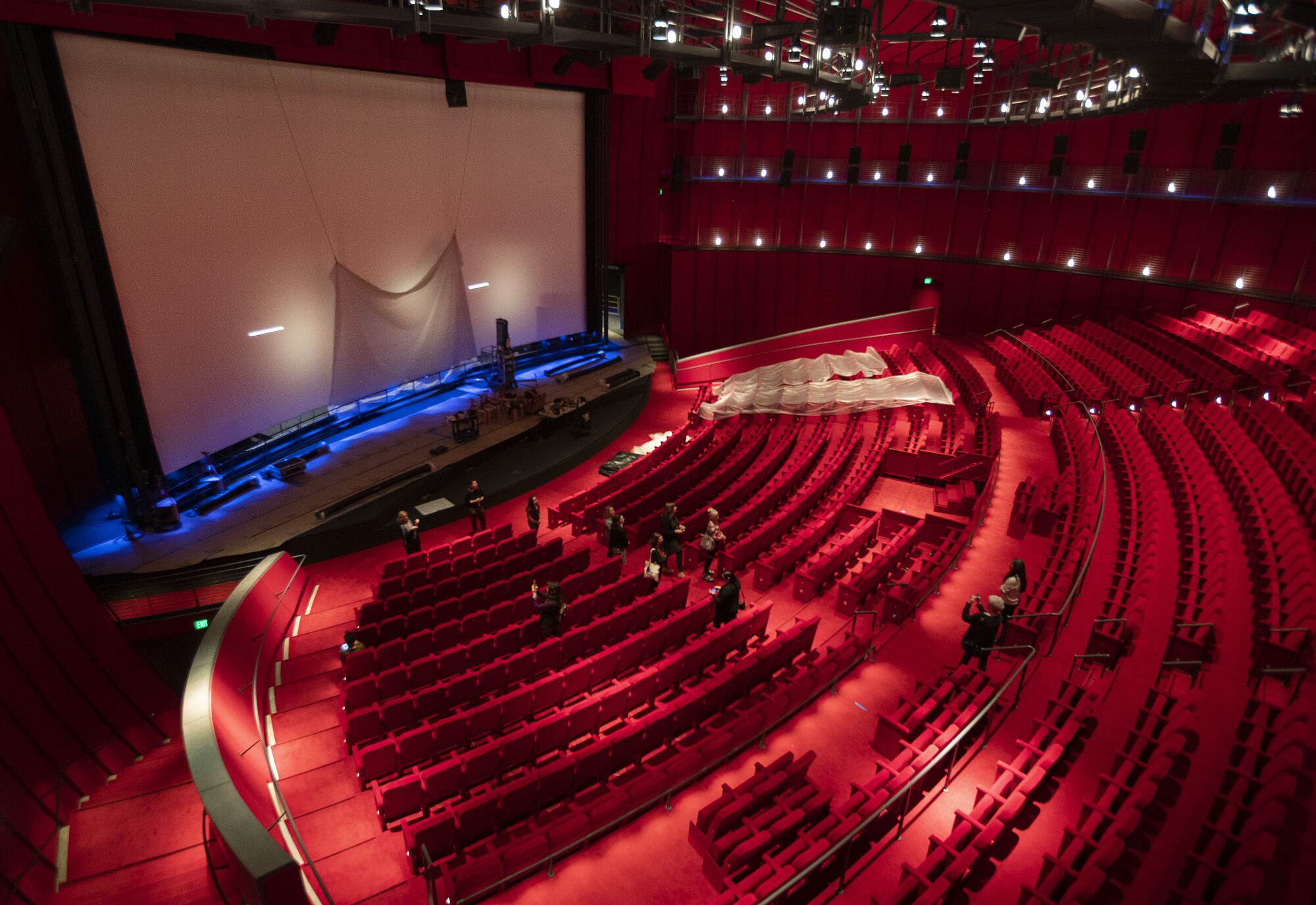 The red interiors of the Geffen theater are seen from inside and from above, revealing the curving lines of the building