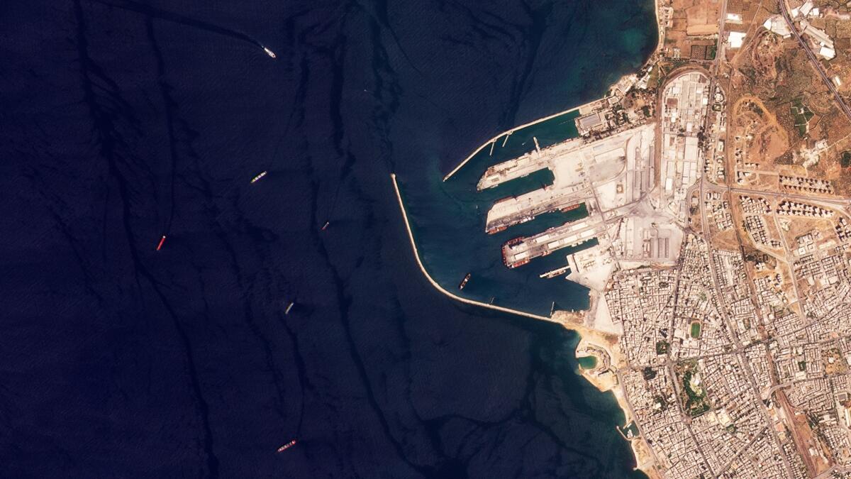 This satellite image from Planet Labs PBC shows the Russian-flagged cargo ship SV Konstantin, the red vessel the furtherest left, off the port in Tartus, Syria, Wednesday, Aug. 17, 2022. The Konstantin, that Ukraine alleges holds stolen grain from territory seized by Moscow amid the war there, appears to have reached the Syrian port of Tartus, satellite images analyzed Thursday by The Associated Press show. (Planet Labs PBC via AP)