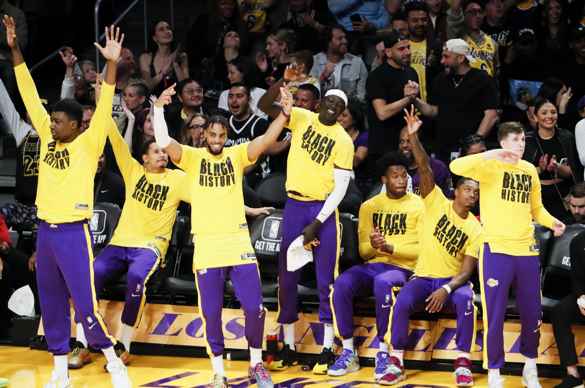 Players on the Lakers bench celebrate after LeBron James makes a shot.