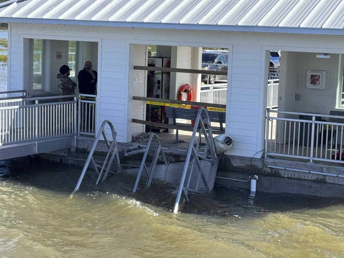 A collapsed gangway hangs in the water.