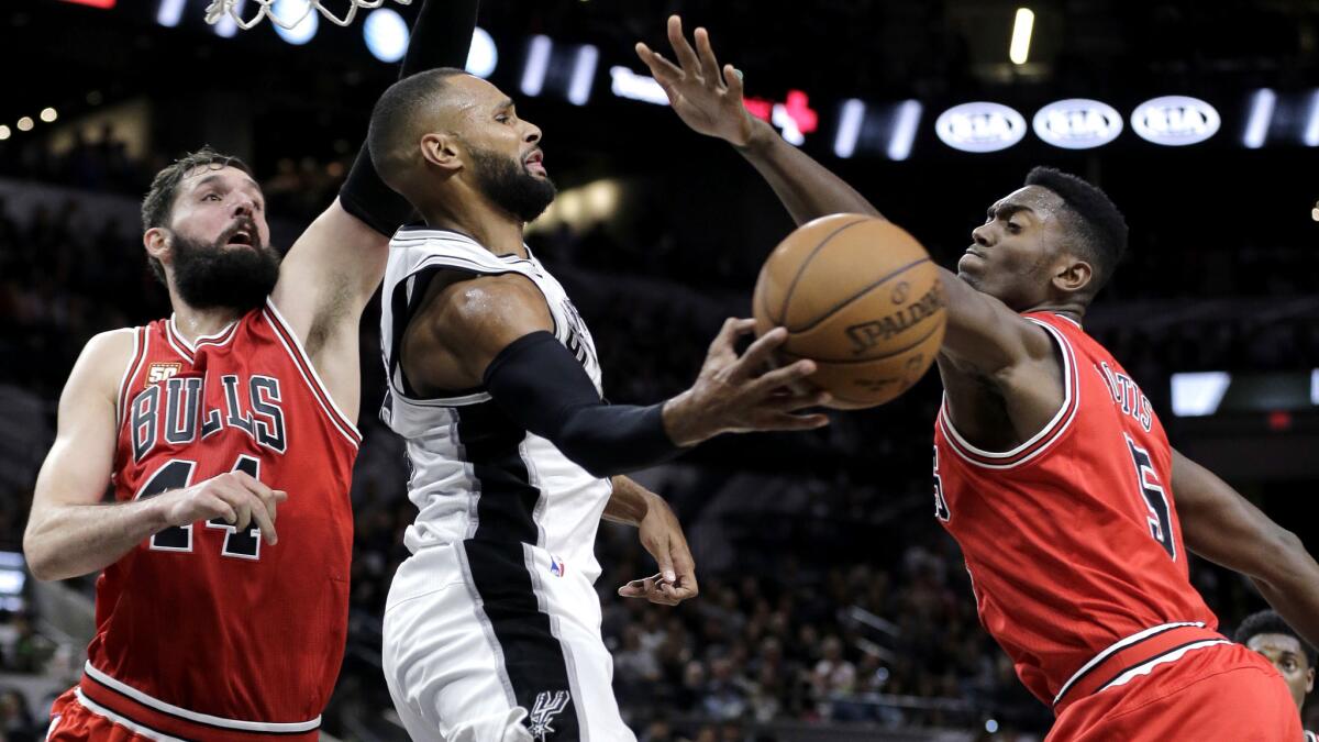 Bulls forwards Nikola Mirotic, left, and forward Bobby Portis (5) force Spurs guard Patty Mills to pass after driving the baseline during a game last season.