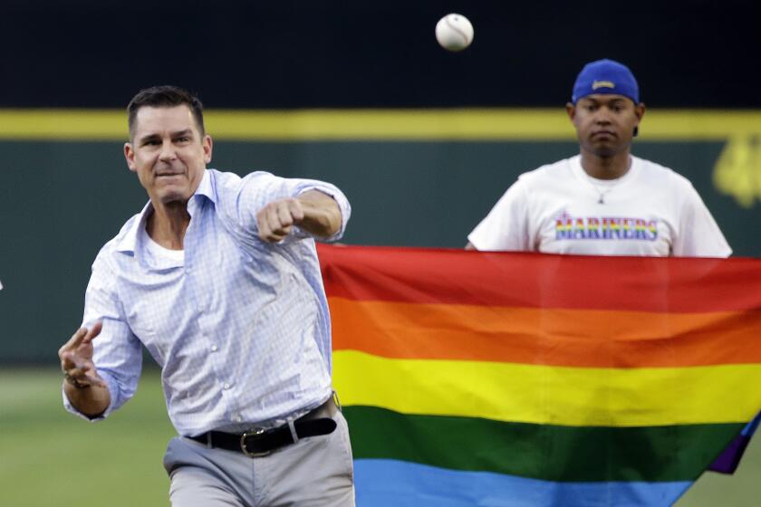 FILE - Billy Bean, Major League Baseball vice president of Social Responsibility & Inclusion, throws out the ceremonial first pitch to Seattle Mariners' Felix Hernandez before a baseball game between the Mariners and Milwaukee Brewers Friday, Aug. 19, 2016, in Seattle. Bean said he doesn't think the absence of an openly gay player is the right way to evaluate inclusivity in the major leagues, just like he doesn't think the sport should be evaluated by a comment that might not be supportive. Bean came out after his playing career. (AP Photo/Elaine Thompson, File)