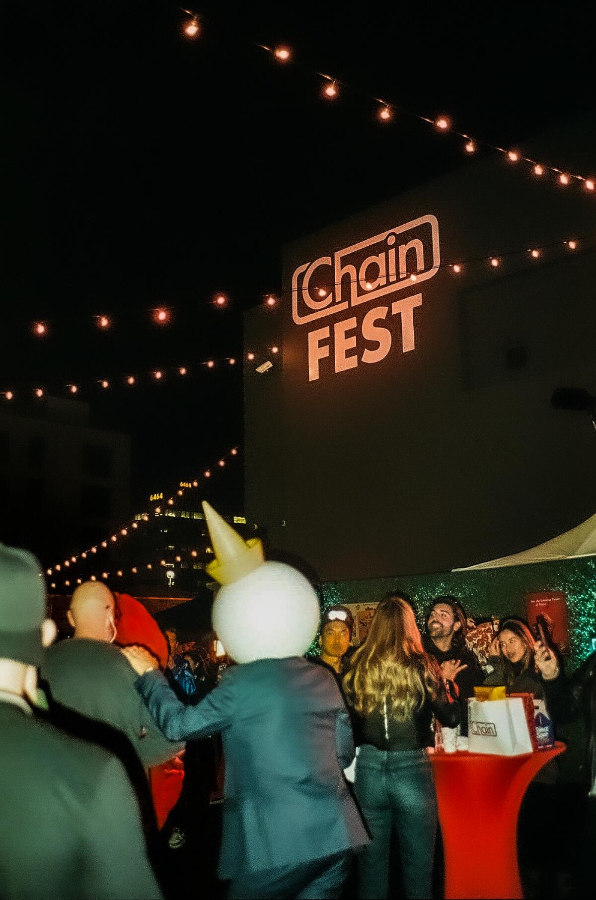 Evening aerial photo of a large ChainFest event. The crowd gathers under the lights of the bulbs.