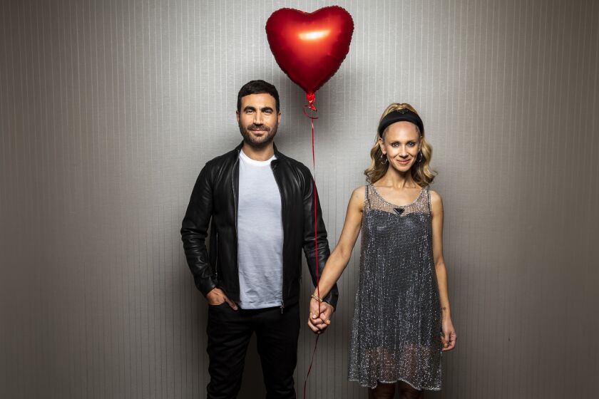 Actors Brett Goldstein, left and Juno Temple holds hands and a red balloon