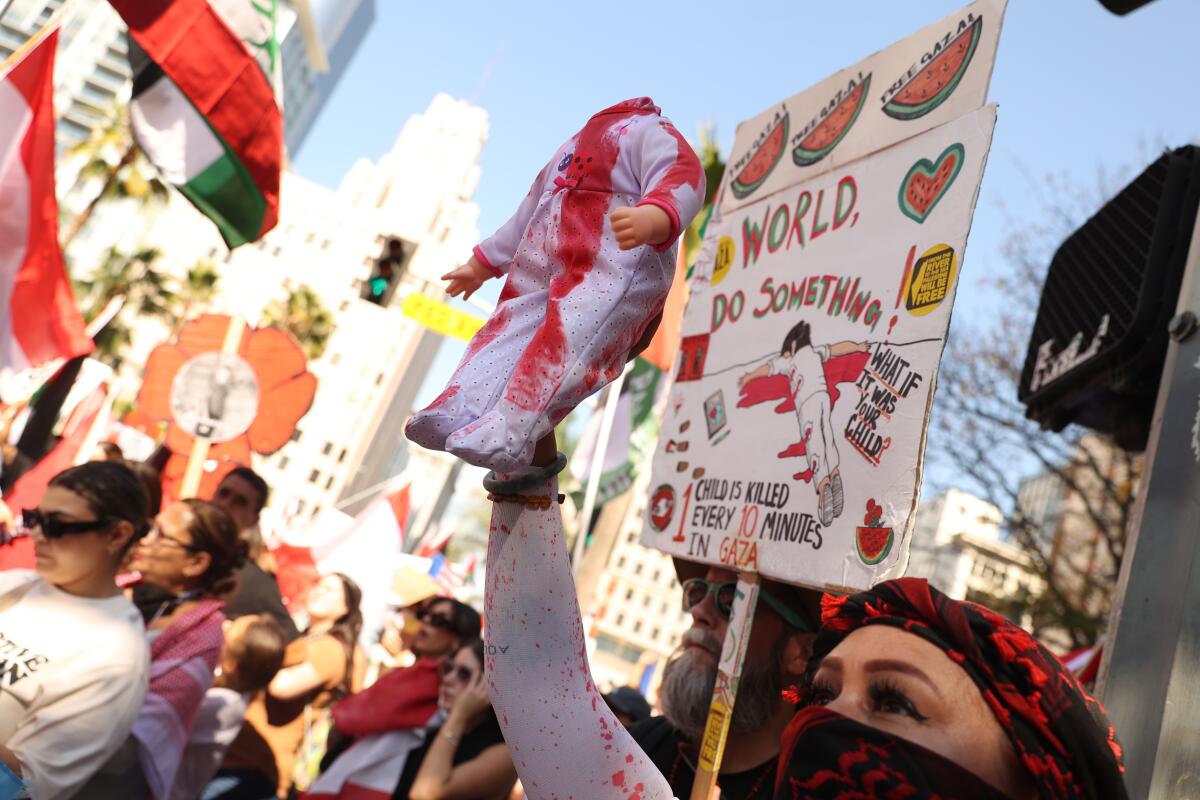 A woman with a shrouded face holds a headless doll with red stains 